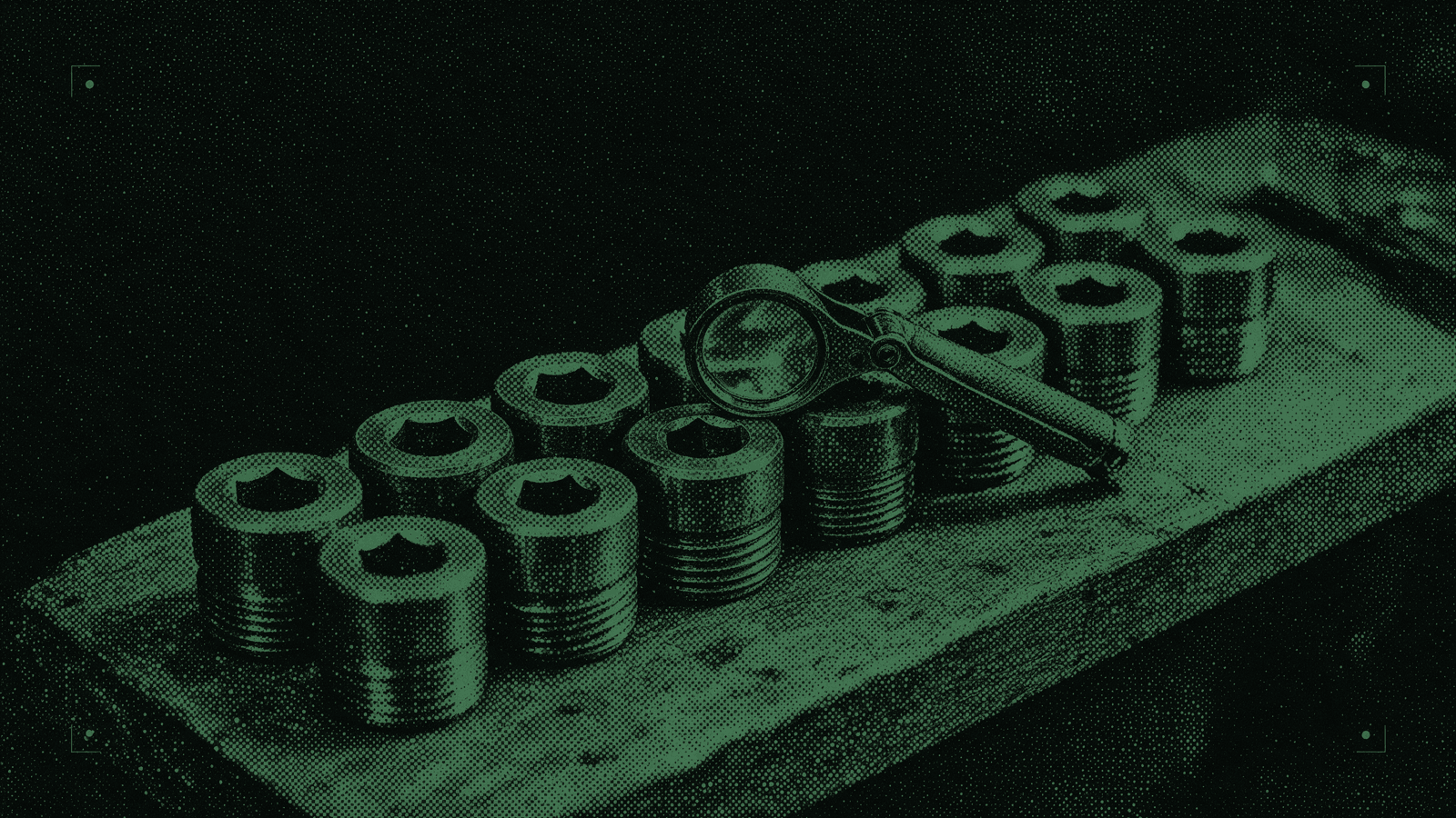 A row of identical machined parts on a bench, one of them under a loupe